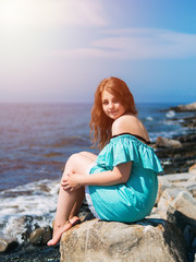 Fototapeta na wymiar girl sitting on a rock by the sea