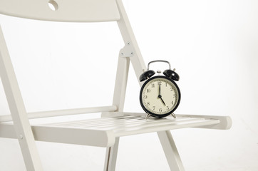 Vintage alarm clock on chair ideal for concept of measuring passing time, waiting,deadlines and...