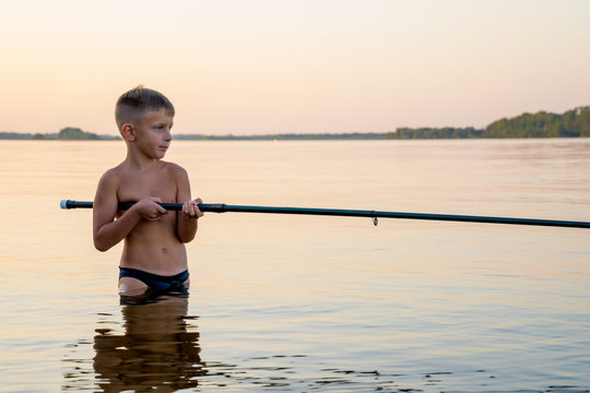 Boy fishing waist deep in water