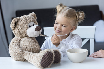 child feeding teddy bear
