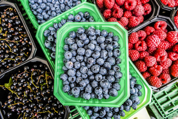 Raspberries, blueberries, currants in baskets sold on local vegetable market during summer.
