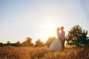 Bride and groom are walking together at sunset near the sea