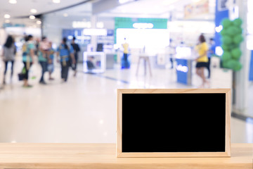 Blank chalkboard on wood table with copy space for your text message or product display in modern shopping mall background.