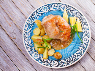 Rabbit with potatoes, lemon and tarragon on blue plate. View from above, top studio shot