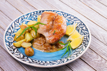 Rabbit with potatoes, lemon and tarragon on blue plate