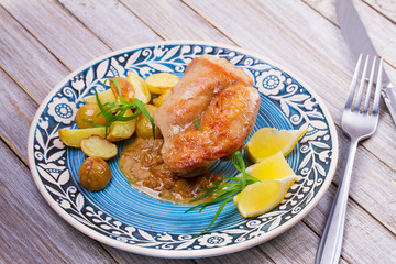 Rabbit with potatoes, lemon and tarragon on blue plate
