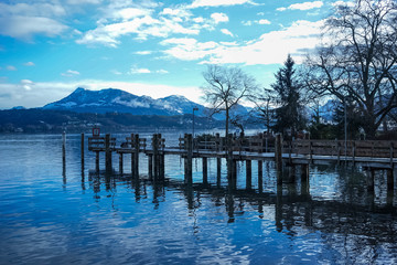 Peaceful wooden pier on a calm blue alpine lake in Lucerne, Switzerland.