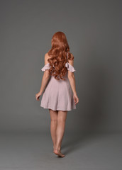 full length portrait of pr a pretty girl wearing simple purple dress, standing pose against a grey...