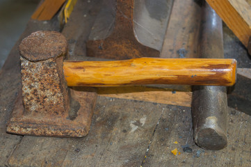 A rusty flatter that is to be struck by a sledgehammer is found in the blacksmith shop.