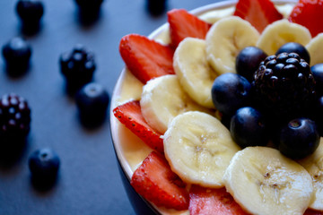 Healthy Fresh Fruit Smoothie Bowl with Strawberries, Bananas, Blueberries on a Black Slate 