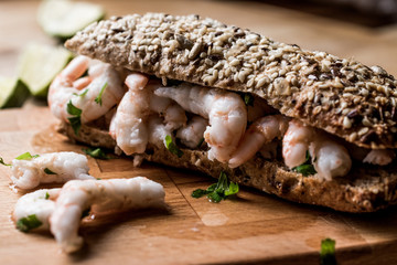 Shrimp Sandwich with lime on wooden surface.