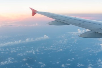 Airplane wing from window seat at sunset with clouds.