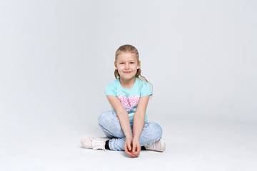 Portrait of a cute girl sitting on the floor on white background