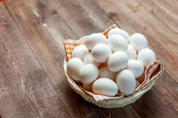 Chicken eggs in basket on wooden background