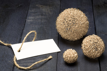 Einladungskarte mit goldenen Dekokugeln auf braunem Holz