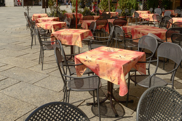 Fototapeta na wymiar empty tables at outdoor cafe on Motta square at Orta san Giulio, Italy