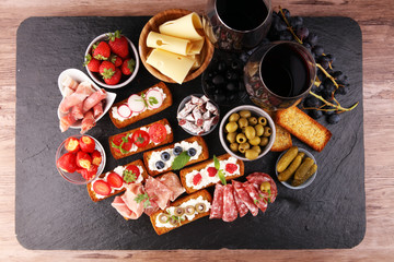 Italian antipasti wine snacks set. Cheese variety, Mediterranean olives, pickles, Prosciutto di Parma, tomatoes and wine in glasses. Spanish tapas