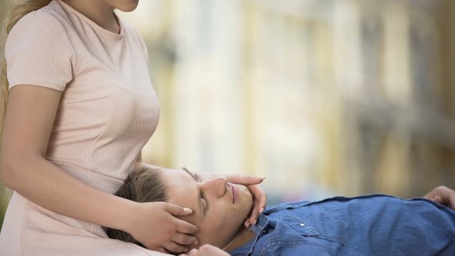 Male holding head on girls lap, girlfriend kissing guy, romantic relationship