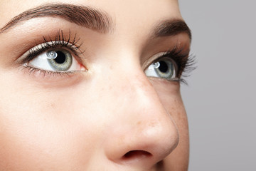 Closeup macro portrait of female face. Human woman open eyes with day beauty makeup. Girl with...