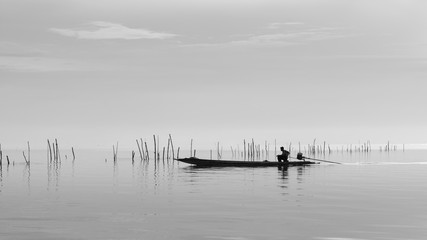 Fisherman on boat in the sea, black and white
