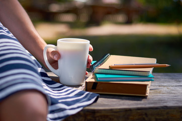 Girl with her hand holds a cup of coffee. Study and work in the park