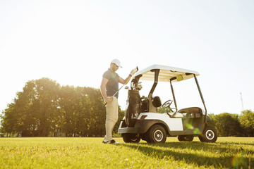 Golfer taking clubs from a bag in a golf cart © Drobot Dean