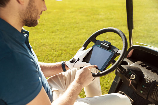 Cropped image of a male golfer sitting in a golf cart