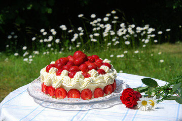 Garden table with a strawberry cake and summer flowers