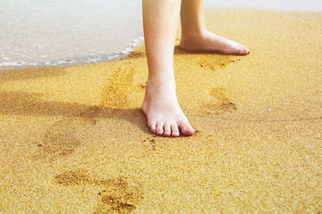 Children's feet on the sand of the sea