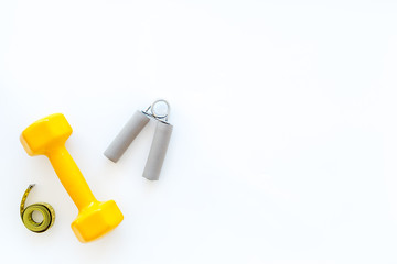 Fitness for loosing weight. Dumbbells, expander and measure tape on white background top view copyspace