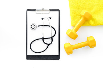 Sport and health. Fitness. Dumbbells and stethoscope on white background top view