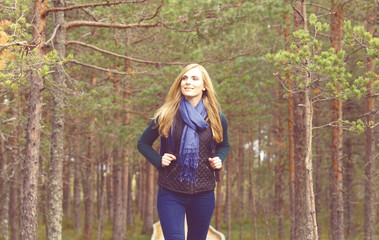 Happy, beautiful blond girl walking in forest and swamps. Camp, tourism, hiking concept.