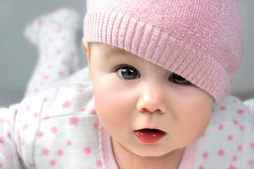 Portrait Baby Mädchen mit Mütze undmit wachem, staunendem direktem Blick