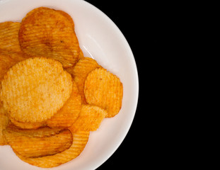 Potato chips on white dish,black background with copy space