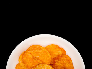 Potato chips on white dish,black background with copy space