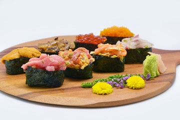 Mixed nigiri sushi (Uni(sea urchin), Ikura (salmon roe), Tobiko (flying fish roe), Otoro,Shutoro, salmon) in brown Chopping board on white background