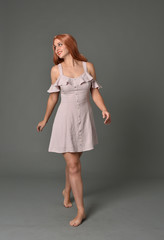 full length portrait of pr a pretty girl wearing simple purple dress, standing pose against a grey background