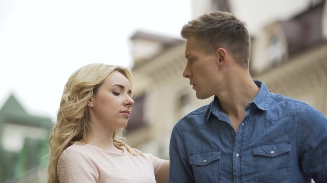 Young man waiting for date, girlfriend coming from behind, apologetic look