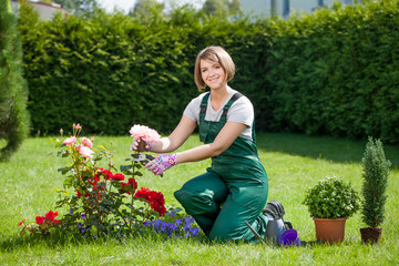 Young smiling woman florist working in the garden.