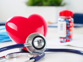 Red heart and stethoscope on doctor table