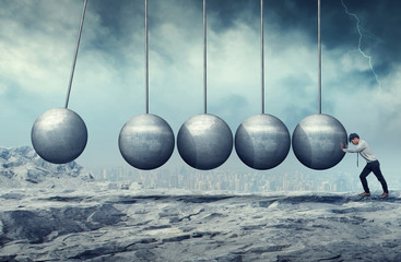 A businessman pushing at a hanging unmoving wrecking ball. Heavy burden. Business heavy tasks and problems concept.