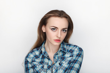 Fototapeta premium Beauty portrait of young adorable fresh looking blonde woman with hair chaos in blue plaid shirt. Emotion and facial expression concept.