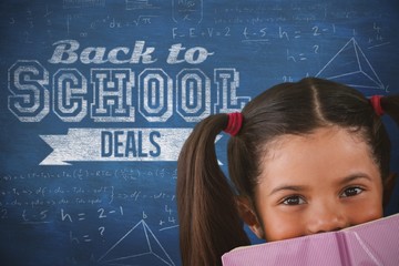 Composite image of schoolgirl covering mouth with book