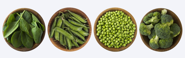 Broccoli, green peas and spinach in wooden bowl. Top view. Vegetables isolated on a white background. 