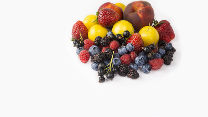 Ripe blueberries, raspberries, black currants, blackberries, strawberries, yellow plums and peaches on white background. Berries with copy space for text.