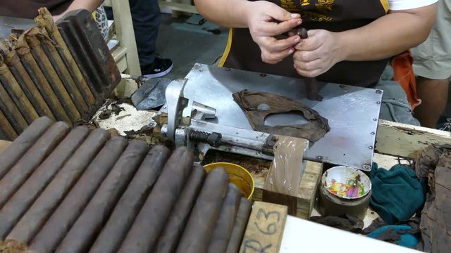 Attach the tip of a cigar leaf to the cigar and cutting the last part in a factory in Esteli Nicaragua