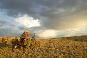 Sunrise hunter and dogs in dramatic arid landscape