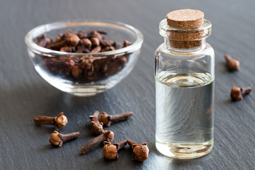 A bottle of clove essential oil with dried cloves