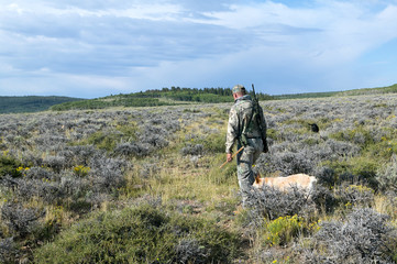 Hunter with dog walking through field for hunting