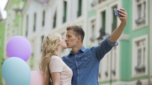 Girlfriend and boyfriend kissing in street and taking selfie, romantic photos